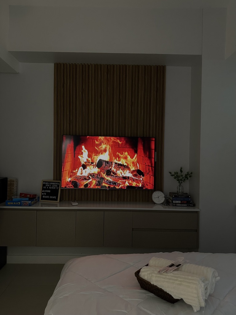 Bedroom at 38 Park Avenue with smart TV on a slatted wood wall and rolled towels on the bed