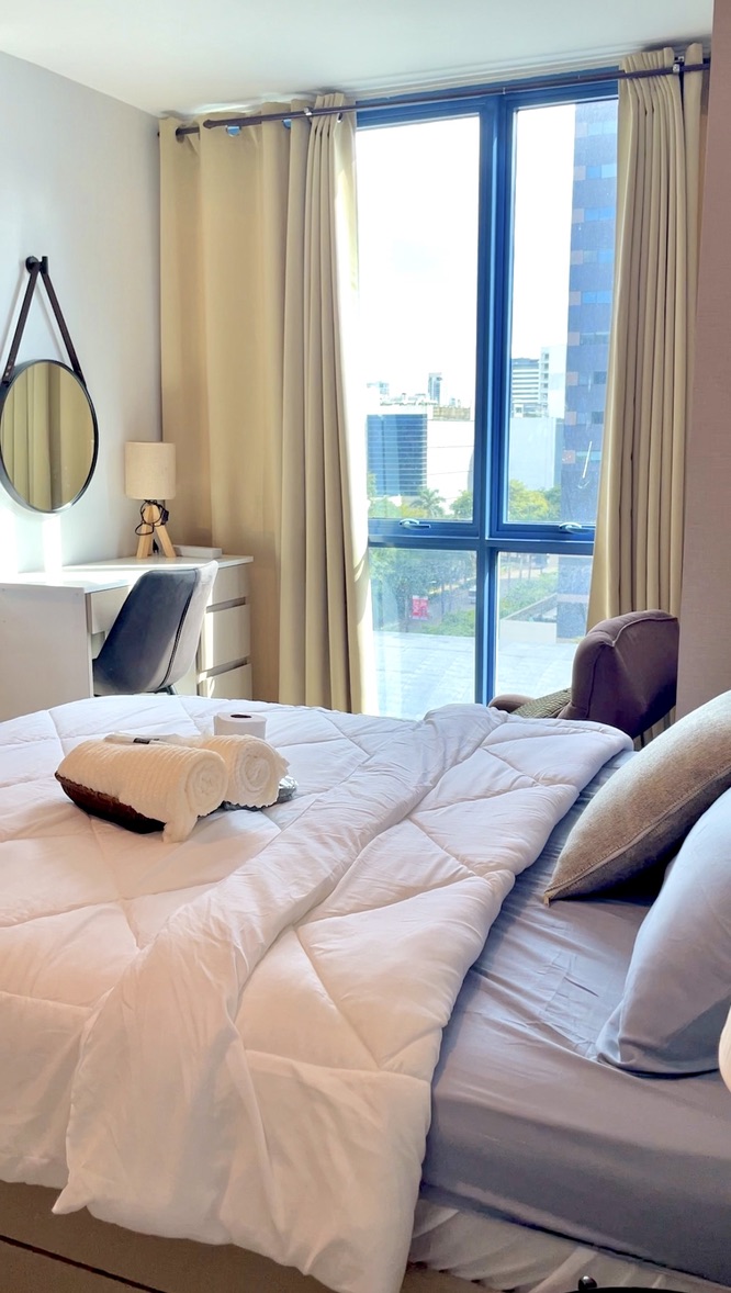 Bright bedroom at 38 Park Avenue with floor-to-ceiling window, desk and fresh linens