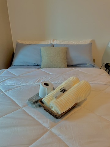 Queen bed at 38 Park Avenue made up with white linens and a towel basket