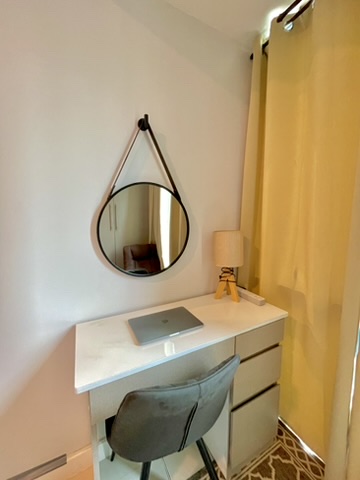 Dedicated workspace at 38 Park Avenue with laptop desk, chair and round mirror