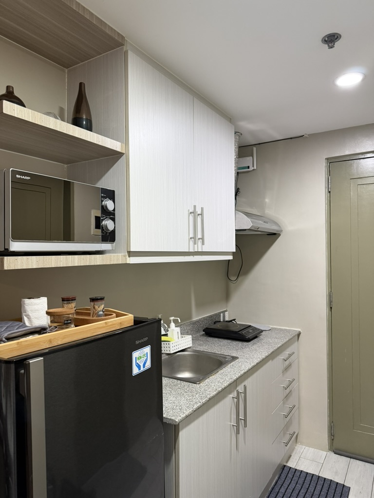 Kitchenette at Cityscape Grand Tower with refrigerator, microwave, sink and overhead cabinets