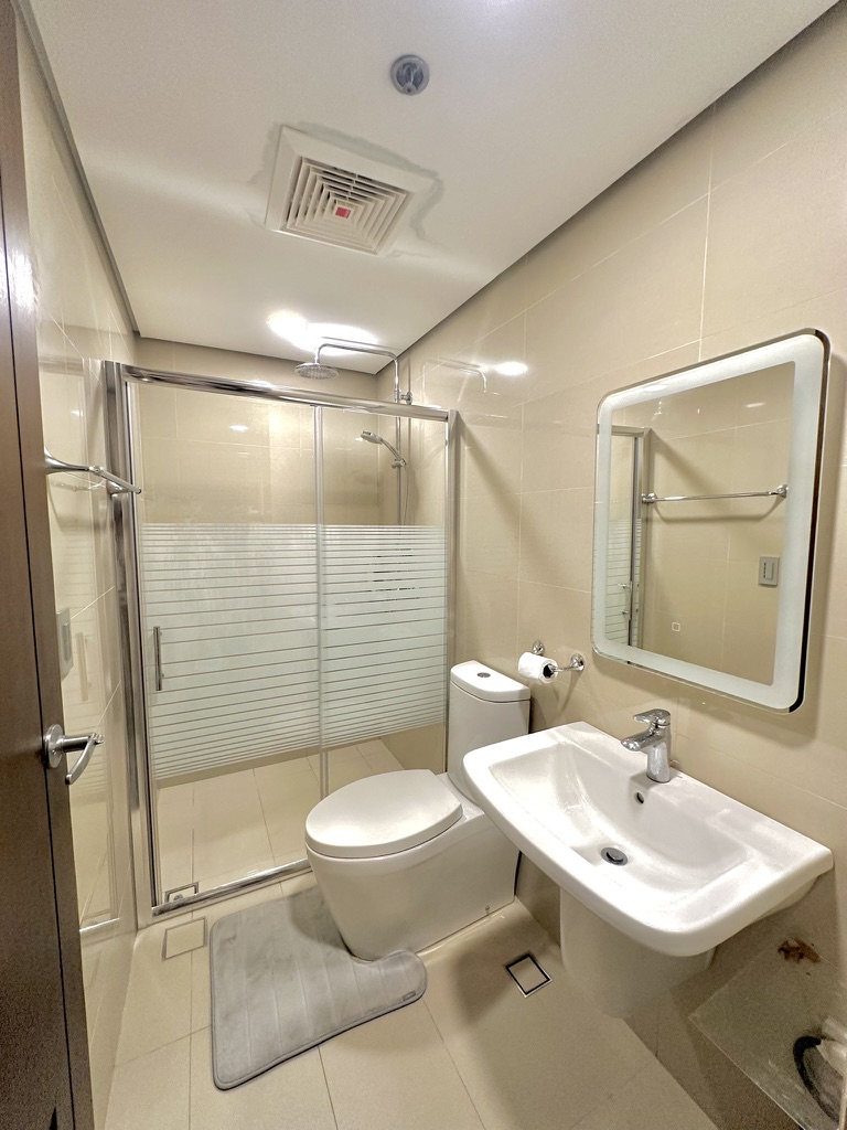 Bathroom at 38 Park Avenue with enclosed glass shower, lit mirror and basin